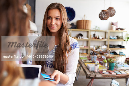 Woman paying shop assistant with credit card in a boutique