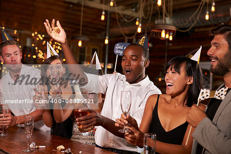 Friends uncorking champagne at a New YearÕs party at a bar