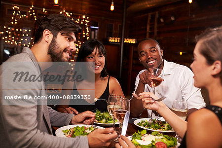 Four friends enjoying dinner and drinks at a restaurant