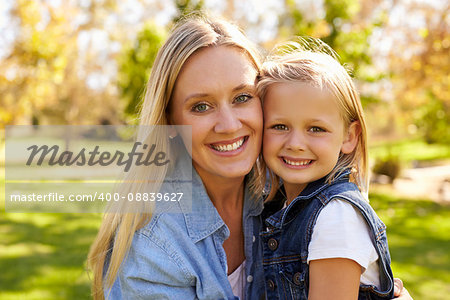 Mother and young daughter smiling to camera, heads together