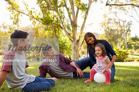 Young mixed race family relaxing with soccer ball in a park