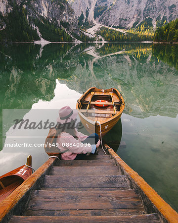 Woman relaxing on pier, Lago di Braies, Dolomite Alps, Val di Braies, South Tyrol, Italy