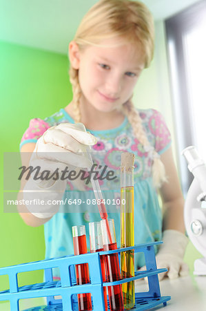 Girl pretending to be scientist removing test tube from rack