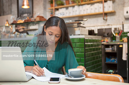 Mid adult woman doing paperwork at cafe table