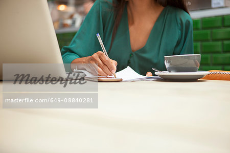 Cropped shot of woman doing paperwork at cafe table