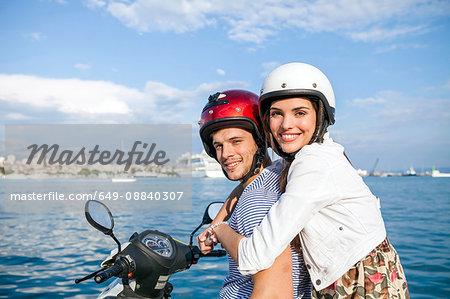 Portrait of young couple riding moped at harbour, Split, Dalmatia, Croatia