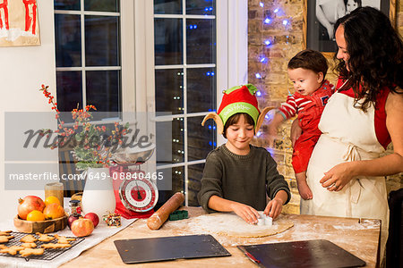 Mature woman preparing Christmas cookies with sons at kitchen counter