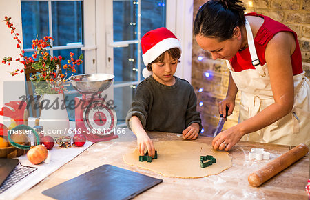 Mature woman preparing Christmas cookies with son at kitchen counter