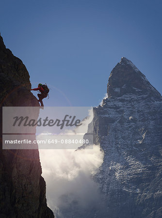 Silhouetted female climber climbing rock face near Matterhorn, Canton Wallis, Switzerland