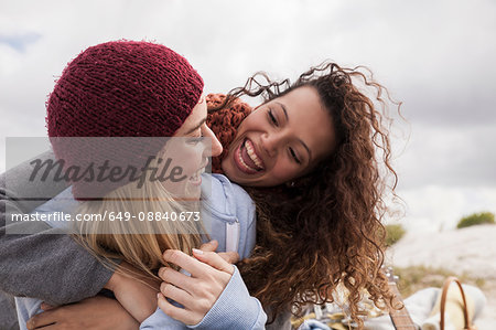 Two young female friends hugging at beach, Western Cape, South Africa