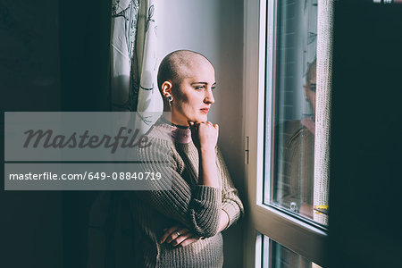 Portrait of young woman with shaved head gazing through window