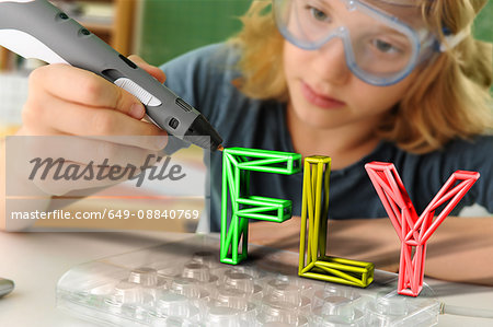 Boy with digital pen and 3D model of capital-lettered word in classroom