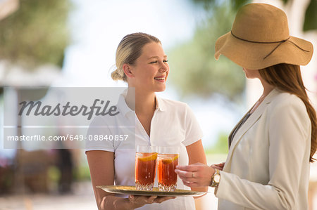 Boutique hotel waitress welcoming young woman with drinks, Majorca, Spain