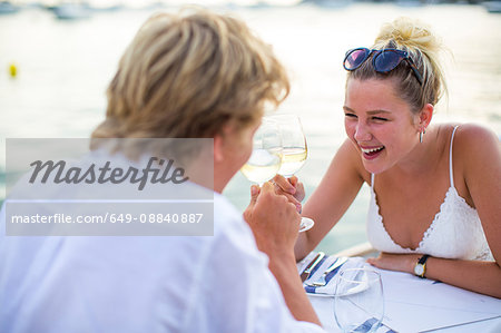 Young couple laughing at waterfront restaurant, Majorca, Spain