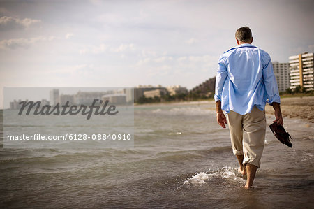 Mature adult man walking through the sea on a beach.
