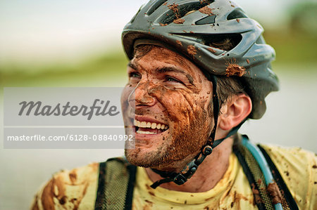 Happy young mountain biker laughing as he is covered in mud.