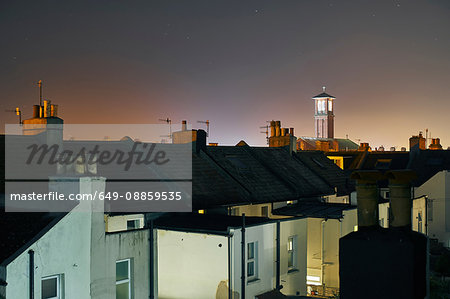 Elevated view of terraced house roof tops and bell tower at night, Brighton, East Sussex, England