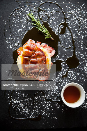 Overhead view of breakfast bacon crumpet with maple syrup on slate