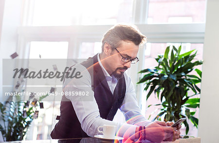 Businessman taking an office coffee break reading smartphone texts