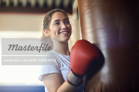Young female boxer punching punch bag in gym