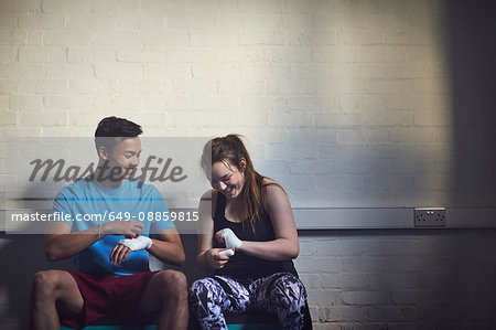 Young male and female boxers wrapping hands in bandages