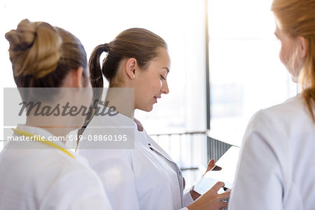 Three young female doctors looking at digital tablet in hospital