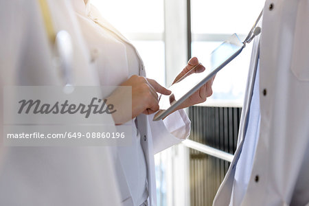 Mid section female doctors using digital tablet touchscreen in hospital