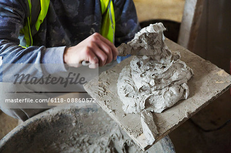 A man holding a plastering board and spreading trowel.