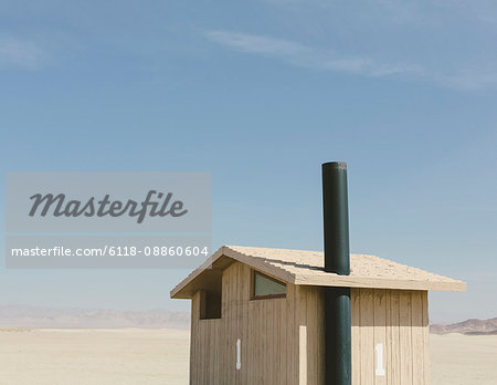 Restroom in a vast desert landscape. A small building.