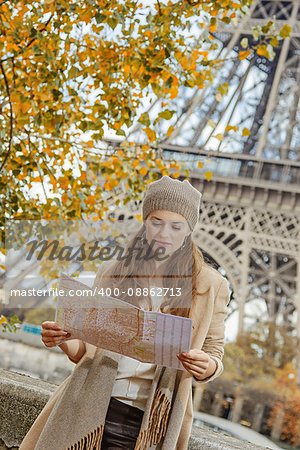 Autumn getaways in Paris. young tourist woman on embankment near Eiffel tower in Paris, France looking at the map