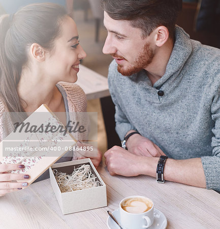 Two people, man and woman in cafe communicate, laughing and enjoying the time spending with each other. Couple in love on a date. A woman receives a gift from a man. Love story and Valentines Day concept