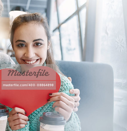 woman smiling and holding a large paper heart. Couple in love on a date. Love story and Valentines Day concept