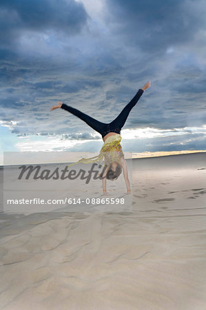 Woman does cartwheel at beach
