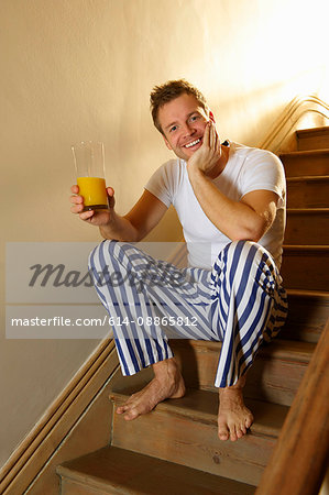 Man sitting on stairs with orange juice