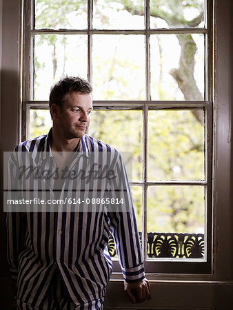 Man sitting by window in his pajamas