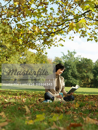 Woman under tree reading book in Autumn