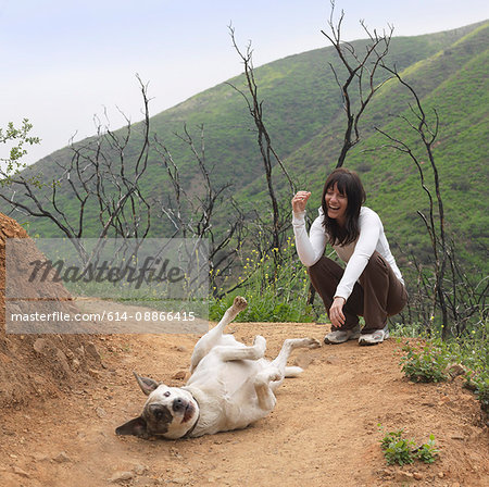 Woman laughing at dog rolling around