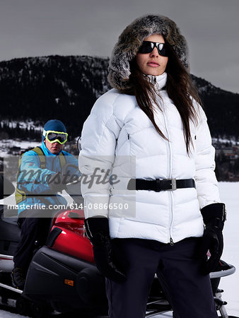 Lady posing in front of man on skidoo.