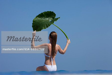 Woman holding leaf in infinity pool