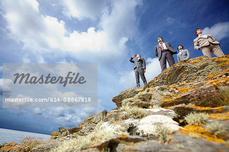 Businessmen standing on cliff edge