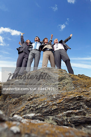 Businessmen cheering on cliff