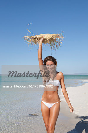 Woman carrying straw hat on beach