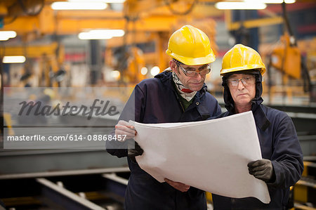 Workers reading blueprints in shipyard