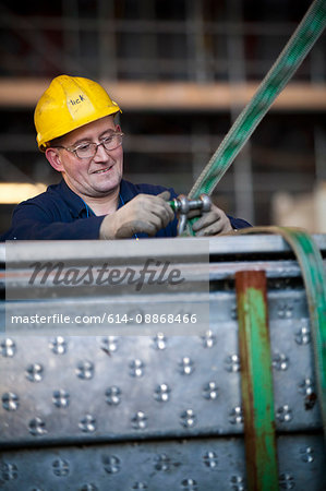 Worker fastening straps at shipyard