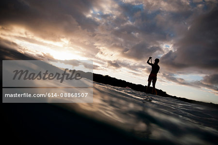 Surfer paddling surfboard in ocean