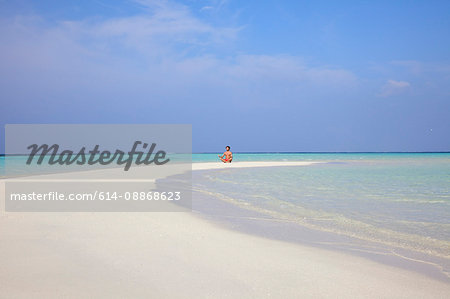 Man meditating on tropical beach
