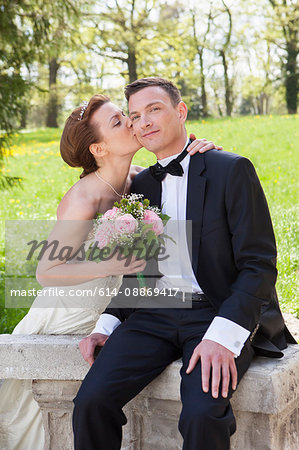 Newlywed couple kissing on wall