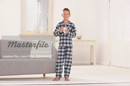 Boy in pajamas with mug in living room