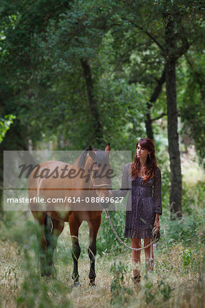 Woman walking horse in forest