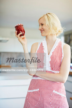 Woman holding jar of jelly in kitchen